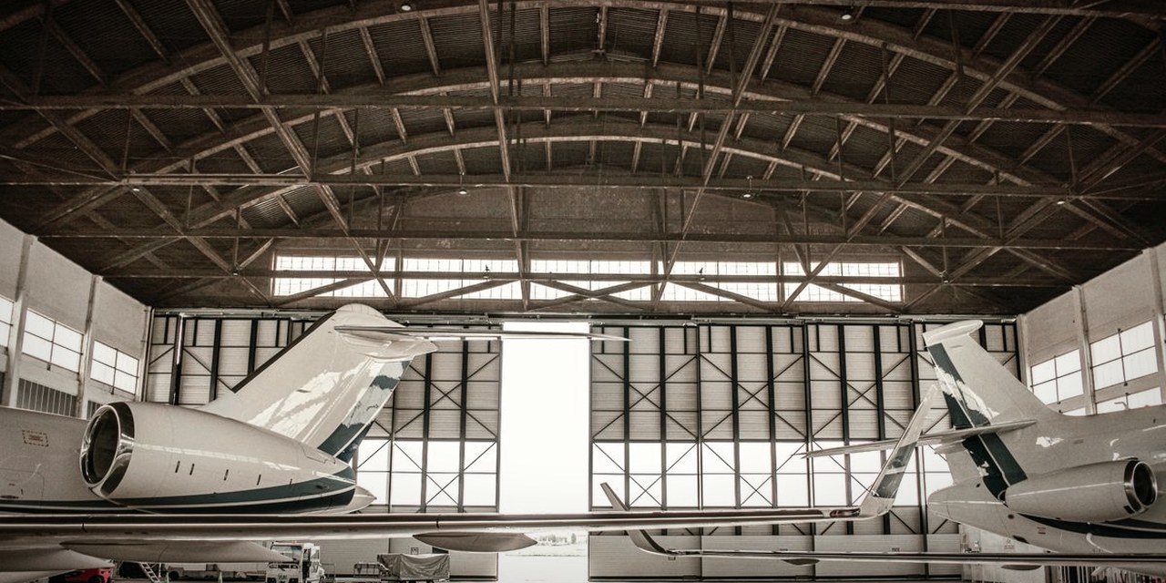 Two private jets inside a large aviation hangar